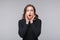 Portrait of shocked afraid woman looking with having wide open mouth gesturing palms, standing gray background