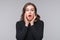 Portrait of shocked afraid woman looking with having wide open mouth gesturing palms, standing gray background