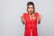 Portrait of shocked beautiful business lady with hairstyle and makeup in red fancy blazer, standing with blocking hands and