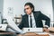 portrait of shocked businessman looking at documents at workplace