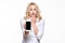 Portrait of shocked pretty blond business woman with hand on her mouth showing mobile phone blank screen isolated over white.