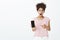 Portrait of shocked stunned cute woman with combed curly hair, dropping jaw and showing smartphone, asking question