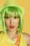Portrait of shocked young woman with green hair against yellow background