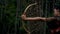 Portrait shoot of female shooting an arrow from the bow in the forest