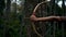 Portrait shoot of female shooting an arrow from the bow in the forest