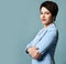 Portrait of short haired brunette businesswoman, experienced manager in blue business suit standing with arms crossed