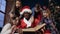 Portrait shot of african boy in the santa claus costume reading book with kids.