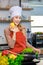 Portrait shot of Asian young beautiful female chef housewife wears white tall cook hat and apron standing smiling posing with