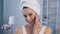 Portrait shot of beautiful young woman with towel on head applying concealer.