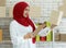 Portrait shot of cute smiling young teenage Muslim woman wearing red hijab standing while holding postage boxes and order