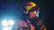 Portrait shot of a fireman in action speaking on the walkie talkie. Fire reflection on the helmet and reflectors in the