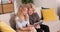 Portrait shot of the gray haired grandmother and teenager granddaughter sitting on the sofa in the cozy room and