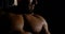 Portrait with the shoulders of a brutal muscular bald male bodybuilder close-up on a black background, he shows the