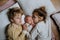 Portrait of siblings cuddling newborn, little baby. Girl lying with her new sibling in bed, closed eyes. Sisterly love