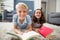 Portrait of siblings lying on rug and reading book in living room