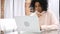 Portrait of sick Afro-American woman coughing while working on laptop