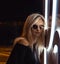 Portrait from side of beauty young blonde hair woman with neon light and sunglasses. Night life