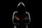 Portrait, silhouette of a man in a hood on a black background, his face is not visible. The concept of a criminal, incognito,