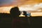 Portrait of a silhouette of a young tourist woman drinking water from a transparent blue bottle in a field, jars at sunset. The gi