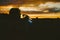 Portrait of a silhouette of a young tourist woman drinking water from a transparent blue bottle in a field, jars at sunset. The gi