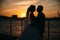 Portrait silhouettes of bride and groom standing on night city background and tenderly looking at each other at sunset