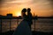 Portrait silhouettes of bride and groom standing on night city background and tenderly looking at each other at sunset