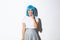 Portrait of silly asian girl in blue wig, smiling and looking curious, standing over white background tempted