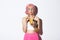 Portrait of silly beautiful girl in pink wig, trick or treating on halloween holiday, eating candies and looking left