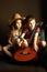 Portrait of sitting caucasian children, wearing western style straw hat and holding guitar