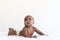 Portrait of a six month crawling African American baby on fluffy white rug, happy smiling adorable sweet little girl kid lying on