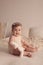 Portrait of a six-month girl sitting on a bed with a toy