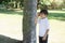Portrait size view of happy school kid standing under big tree in hot sunny day early Autumn, Cute Child boy playing in the park