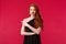 Portrait of skeptical, picky elegant redhead girlfriend in stylish black dress, grimacing disappointed, pointing finger