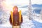 Portrait of skier in protective mask with yellow skis on background of snowy mountains and forest, sunlight