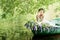 Portrait of slavic or baltic woman with wreath sitting in boat with flowers. Summer