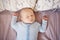 Portrait of sleeping funny white Caucasian blond little baby boy newborn in blue clothes lying on bed with his hands up