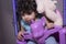 Portrait of a sleepy little baby girl on unicorn swing with teddy bear doll on her
