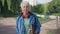 Portrait of slim senior woman with grey hair posing with skateboard outdoors smiling. Positive sportive active Caucasian