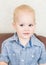 Portrait small baby boy sitting on chair and looking into camera. Close-up tot