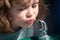 Portrait of a small blond boy drinking water outdoor in park, closeup. Cute kids face. Positive emotional child. Thirsty