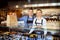 Portrait of small business owner smiling behind counter inside eatery holding food order for home delivery