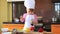 Portrait small child in chef suit helps her mother cook in the kitchen