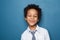 Portrait of small clever black child boy smiling on blue background