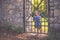 Portrait of a small four year old girl at a old iron gate in a park in autumn.