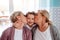 A portrait of small girl with mother and grandmother at home, kissing.