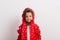 Portrait of a small girl with red anorak in studio on a white background.