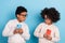 Portrait of small little trendy pre-teen friends using device hiding play game app smm  over bright blue color