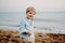 A portrait of small toddler boy standing on beach on summer holiday.