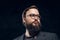 Portrait of a smart bearded man in glasses in a dark studio