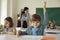 Portrait of smart clever primary school student raising hand smiling to camera